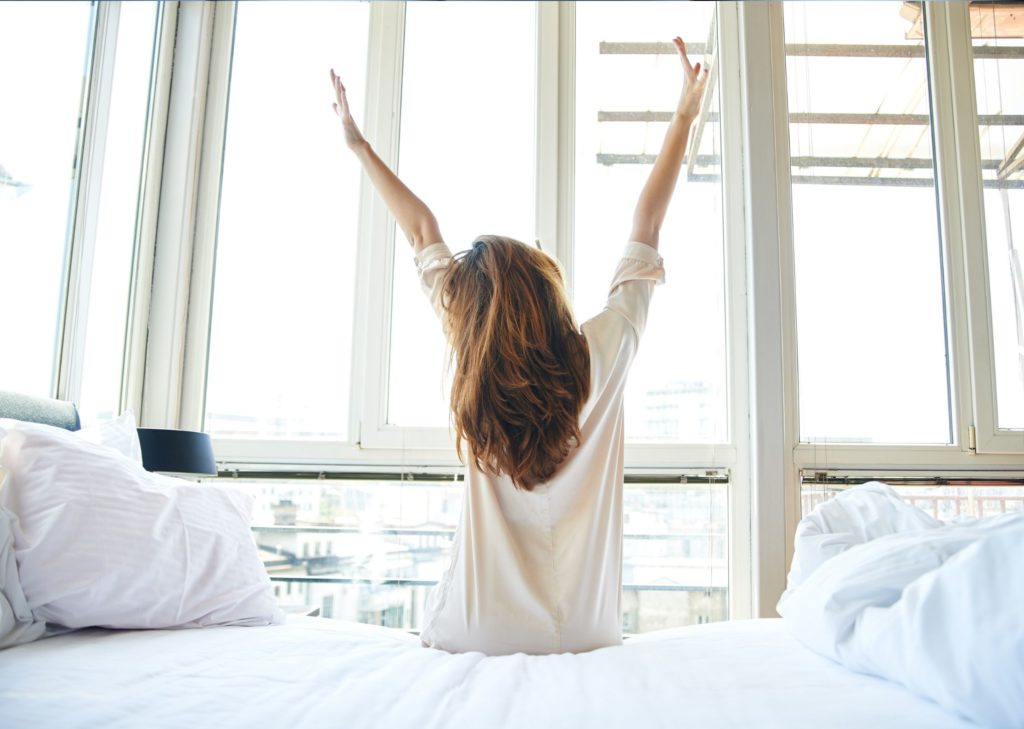 beautiful woman arms up getting out of bed morning routine