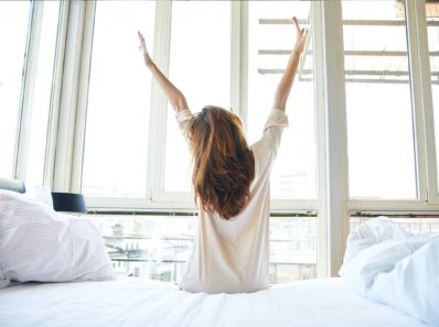 femme belle bras en l'air lever du lit routine matin