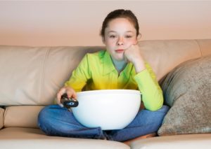 child in front of the TV with popcorn on the sofa